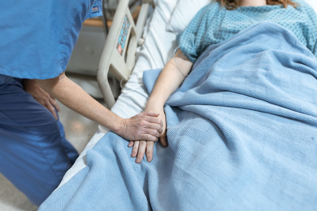 Nurse offering comfort and compassionate care by holding a patient's hand